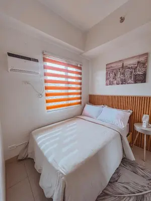 a bedroom with a large white bed and a window at FOG Staycation in Manila