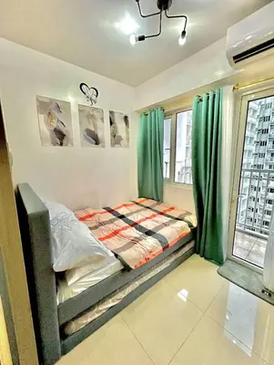 a bedroom with a bed with green curtains at SHORE 1 MALL OF ASIA Staycation in Manila