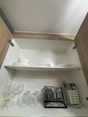 a cupboard filled with glasses and plates and dishes at Modern apartment with balcony and Pool View in Manila