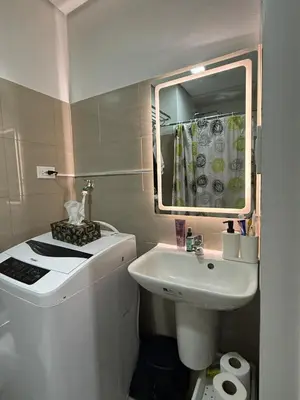 a white bathroom with a sink and a mirror at Modern apartment with balcony and Pool View in Manila