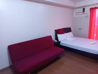 a red couch and a bed in a room at Grand Soho Makati in Manila