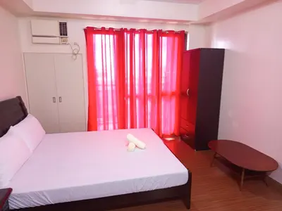a bedroom with a white bed and red curtains at Grand Soho Makati in Manila