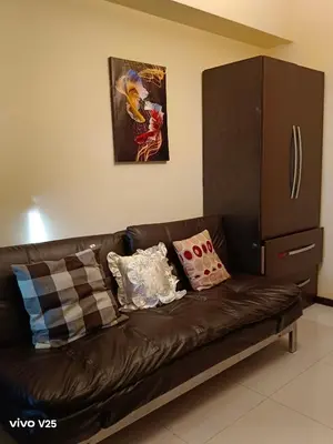 a brown leather couch with pillows in a living room at Sea Residences Joy in Manila