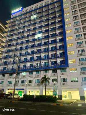 a large white building with a blue sign on it at Sea Residences Joy in Manila