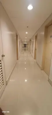 an empty hallway in a building with white floors at Sea Residences Joy in Manila