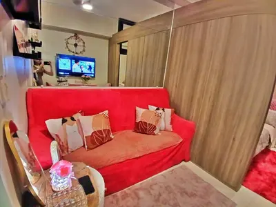 a living room with a red couch with pillows at Blush & Glam at SMDC Fame Residences Tower 3 in Manila