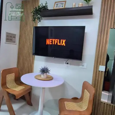 a tv on a wall with a white table and chairs at 1128 Positano in Manila