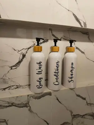 three white shampoo bottles on a shelf in a bathroom at Cozy Private Retreat with Kitchen & Balcony in Bacoor