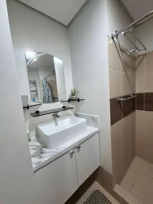 a white bathroom with a sink and a mirror at Cozy Hotel-Style 1 Bedroom Condo Unit Bryant Tower 12E at Eastbay Residences by Rockwell in Manila