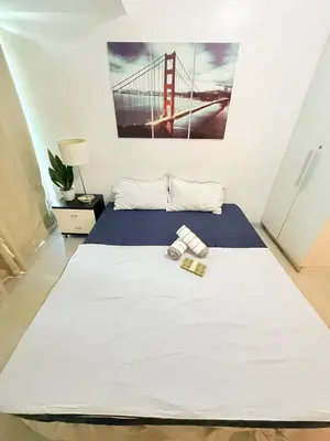 a bedroom with a white bed with a bridge picture on the wall at Azure Destiny's Suites 1912 in Manila