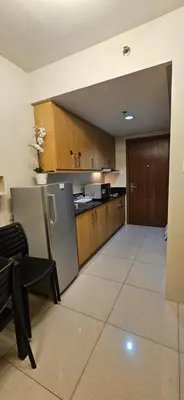 a kitchen with wooden cabinets and a stainless steel refrigerator at Low Floor 1BR Balcony Shell near MOA Shell001 in Manila