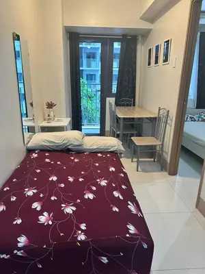 a bedroom with a bed with a red blanket with flowers at Gateway Mall of Asia Near Airport in Manila