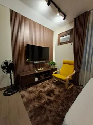 a living room with a yellow chair and a flat screen tv at THE Faithful Nest in General Trias