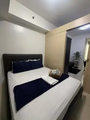a bedroom with a large bed with blue pillows at Sea Residences StaycationAtMOA in Manila
