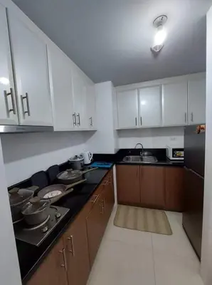 a kitchen with white cabinets and a black counter top at Sleep and Fly Condotel in Manila