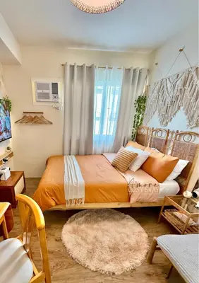 a bedroom with a bed with an orange bedspread at A'more Cosy Stay Near Nuvali at Fullerton Suites in Silang