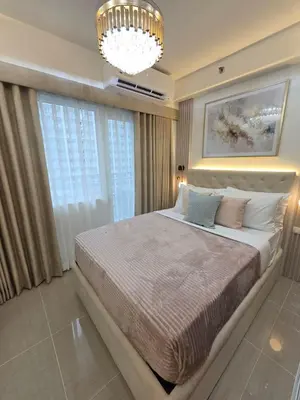 a bedroom with a large bed and a chandelier at Royal Suites at Shore Residences near SM MOA and Airport in Manila