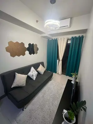 a living room with a black couch and green curtains at Calm Corner near Mall of Asia in Manila