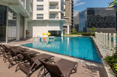 a swimming pool with chairs and a building at Uptown BGC Condo in Manila