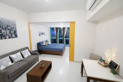a living room with a couch and a bed at Modern 1BR One Uptown Residence Walk to UptownMall in Manila