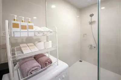 a bathroom with a shower and a towel rack at Modern 1BR One Uptown Residence Walk to UptownMall in Manila