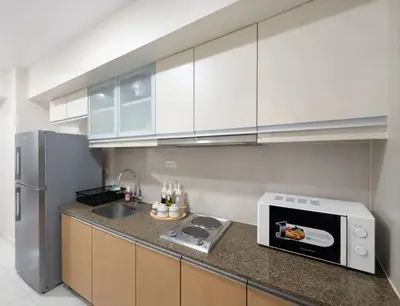 a kitchen with white cabinets and a microwave at Modern 1BR One Uptown Residence Walk to UptownMall in Manila