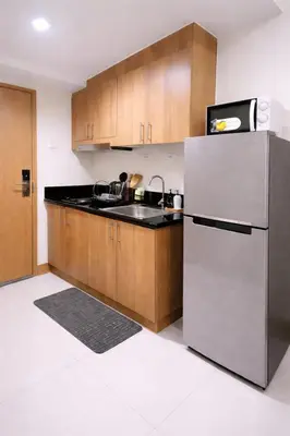 a kitchen with a stainless steel refrigerator and wooden cabinets at Cozy Unit at Shore 3 Residences Tower 4 near MOA in Manila
