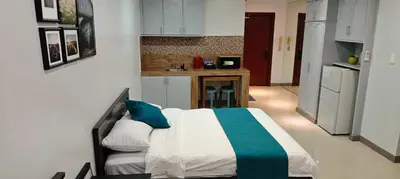 a bedroom with a bed and a small kitchen at Touristation @ Crowne Bay Tower in Manila