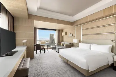 a hotel room with a bed and a desk with a television at Shangri-La The Fort, Manila in Manila