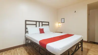 a bedroom with a large white bed with a red blanket at RedDoorz at Elegance Guest House near NAIA T3 in Manila