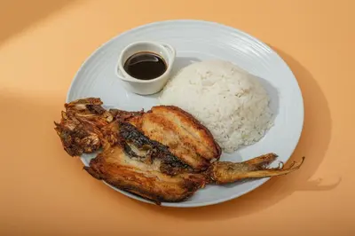 a plate of chicken and rice with a side of sauce at Hotel Juliano in Manila