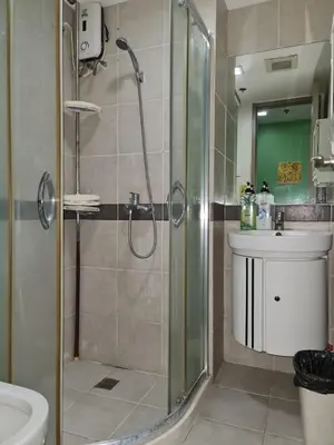 a bathroom with a shower and a toilet and a sink at Solemare Parksuites Condominium - Condo R Us in Manila