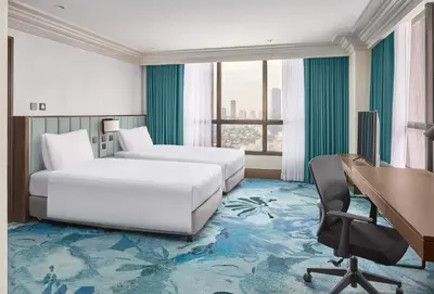 a hotel room with two beds and a desk at Holiday Inn & Suites Manila Galleria by IHG in Manila