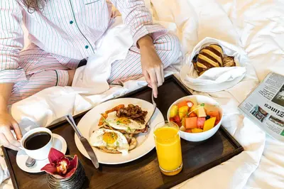 a person laying in bed with a tray of breakfast food at Shangri-La Residences The Fort, Manila in Manila