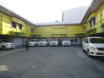 a yellow building with cars parked in a parking lot at Park Bed and Breakfast Hotel Pasay in Manila