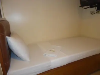 a small bed with a white pillow and a scale at Park Bed and Breakfast Hotel Pasay in Manila
