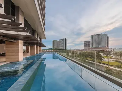 a swimming pool on the roof of a building with a city skyline at Somerset Alabang Manila in Manila