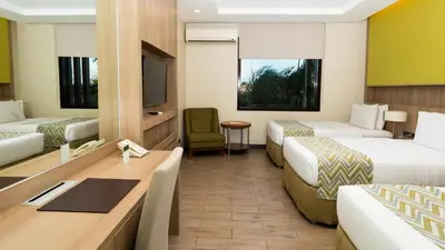 a hotel room with two beds and a desk at The Bayleaf Cavite in General Trias