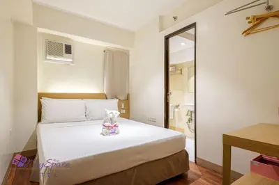 a bedroom with a white bed and a mirror at MySpace Hotel @BGC in Manila