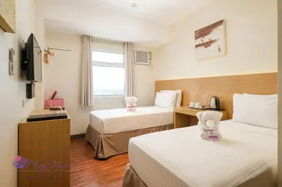 a hotel room with two beds and a television at MySpace Hotel @BGC in Manila
