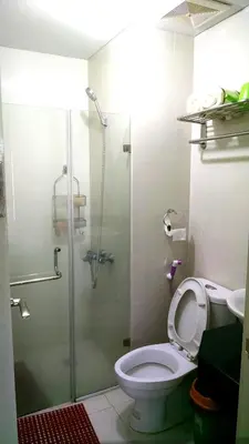 a bathroom with a toilet and a glass shower at 3N Palm Tree Villas in Manila