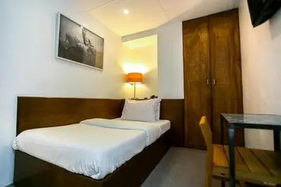 a small bedroom with a bed and a table and a desk at Hotel Durban in Manila