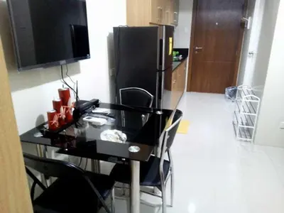 a black table with chairs and a black refrigerator at Condo At Shell Residences in Manila