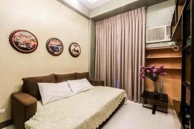 a bedroom with a bed and a television and flowers at PRS at One Palm Tree Villa near T3 Airport in Manila