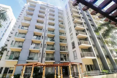 a tall white building with palm trees in front of it at PRS at One Palm Tree Villa near T3 Airport in Manila