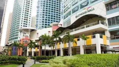 a building with palm trees in front of tall buildings at Eastwood Residence Above Eastwood Mall in Manila