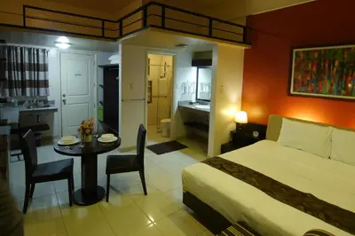 a bedroom with a bed and a table and a bathroom at New Manila Suites in Manila