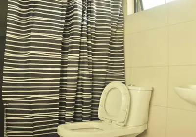 a bathroom with a toilet with a black and white shower curtain at Ortigas Budget Hotel - Kapitolyo in Manila