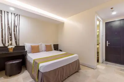 a bedroom with a bed and a desk in a room at Selah Garden Hotel Manila in Manila