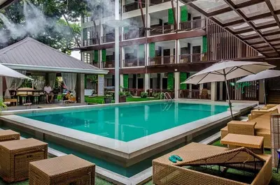 a swimming pool with chairs and umbrellas next to a building at Selah Garden Hotel Manila in Manila